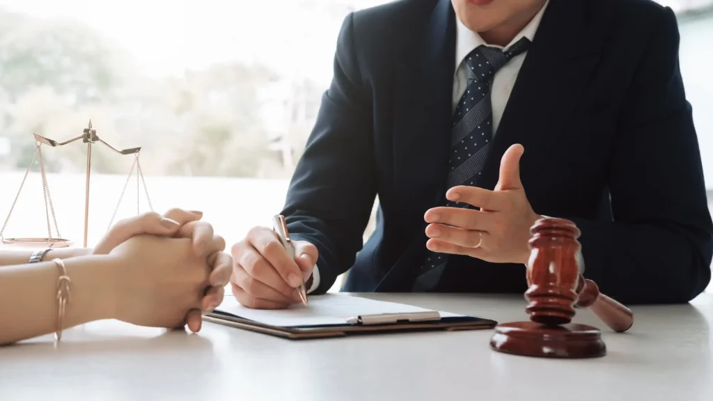 Close-up of a lawyer discussing with a client, with legal documents and a gavel on the table