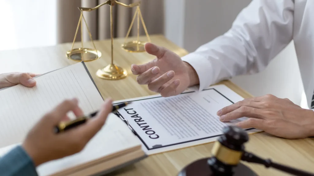 Lawyer and client discussing a contract with a gavel and legal scales on the table.
